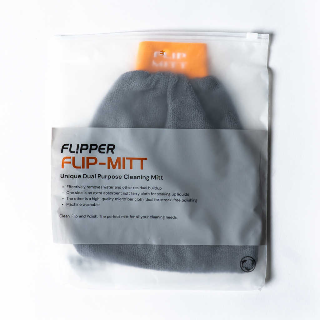 A gray FLIP-MITT microfiber cleaning mitt is shown in a clear plastic bag with an orange insert and a label.